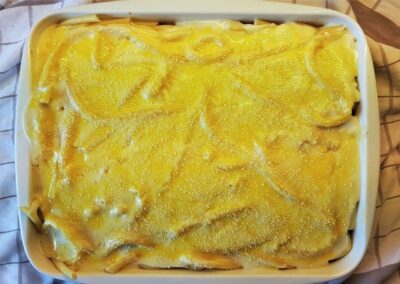 Preparing pastitsio, adding the bechamel sauce